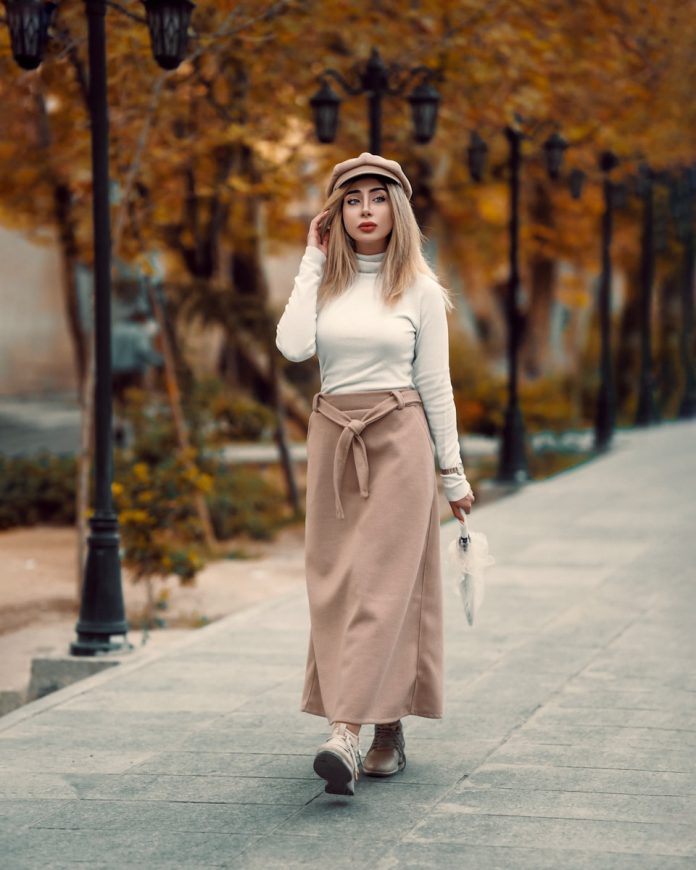 A woman walking down a sidewalk in a long skirt