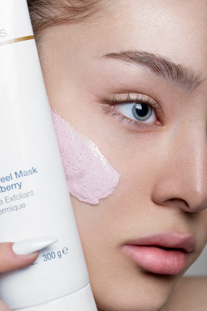 a woman holding a tube of cream on her face