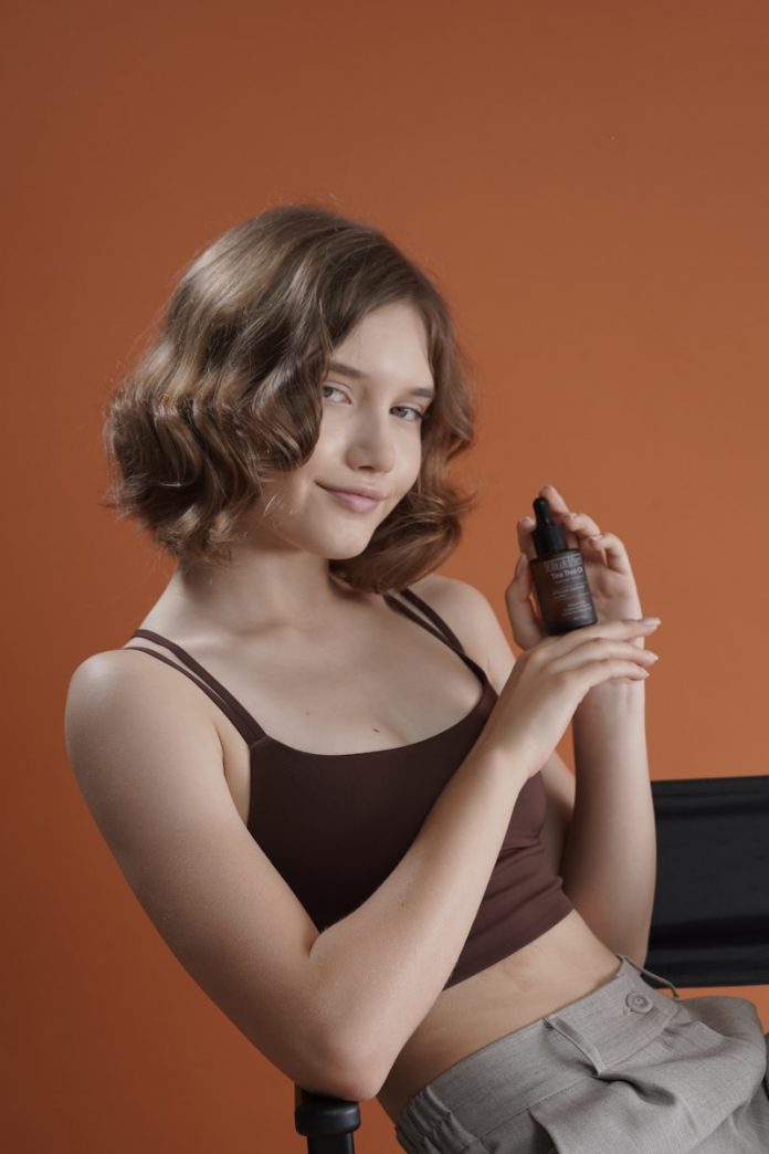 Young woman holds a skincare product bottle.