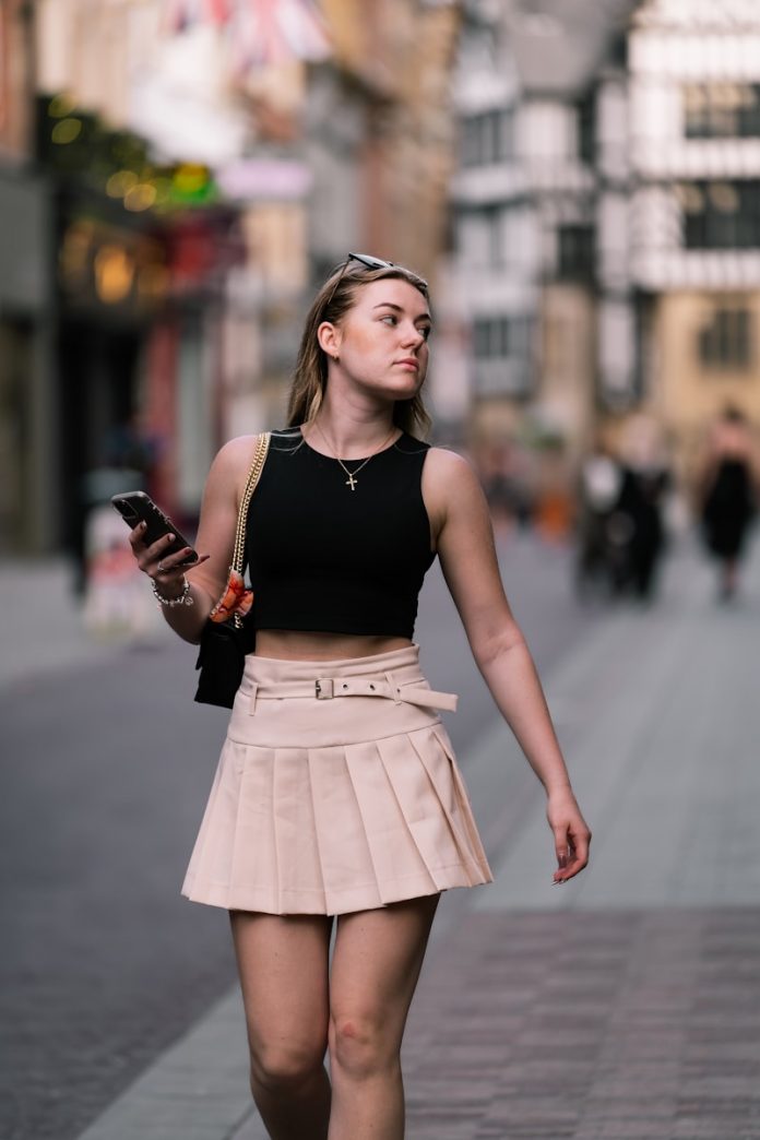 A woman walking down a street with a cell phone in her hand