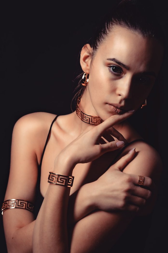 Woman wearing ornate gold greek key jewelry set