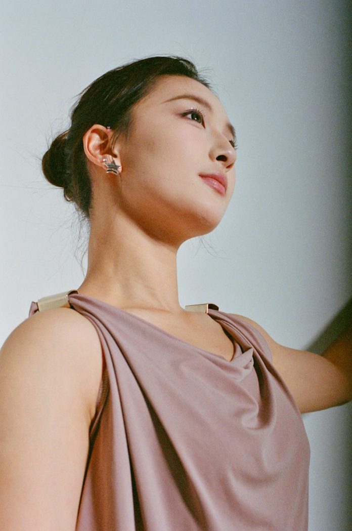 A young woman with hair in a bun looks up.